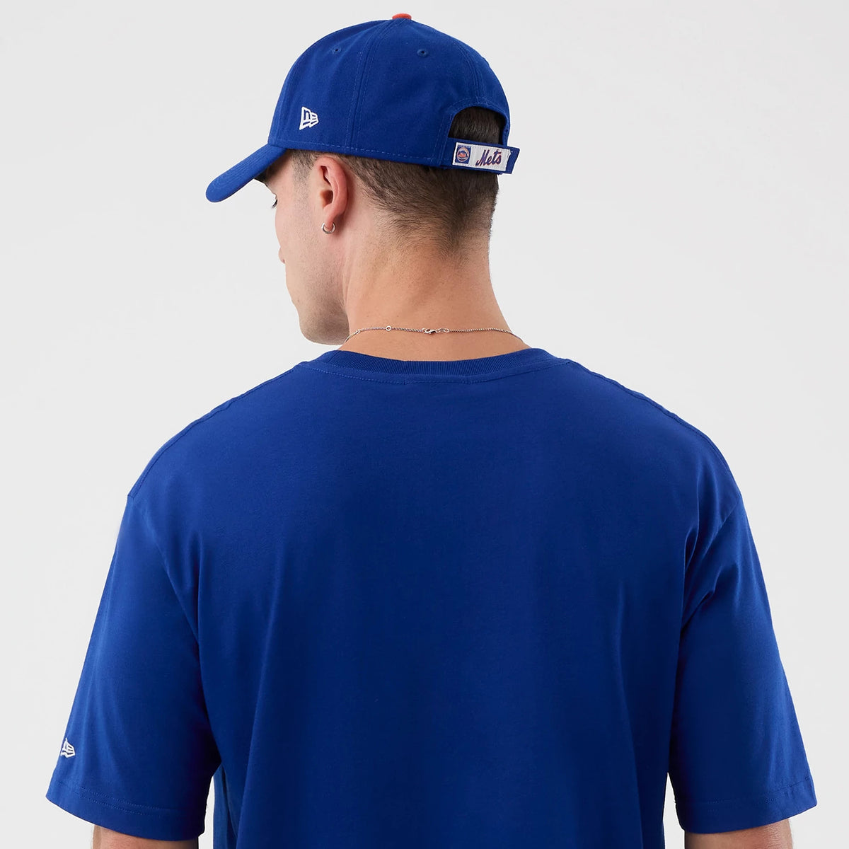 New Era New York Mets MLB Sport Classic Blue T-Shirt, back view on-model featuring plain blue fabric, a small embroidered New Era logo on the left sleeve, paired with a matching blue cap showcasing a Mets logo on the strap.