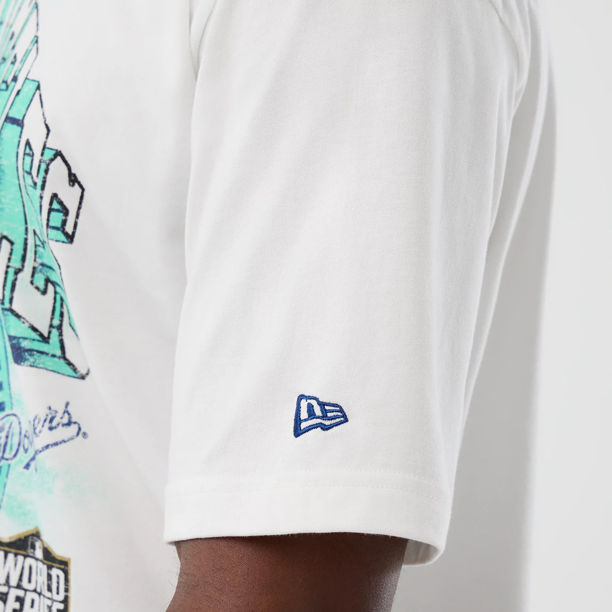 New Era LA Dodgers MLB Sport Script Classic White T-Shirt, side view showing a blue embroidered New Era logo on the sleeve and part of the graphic in aqua and black extending across the back.