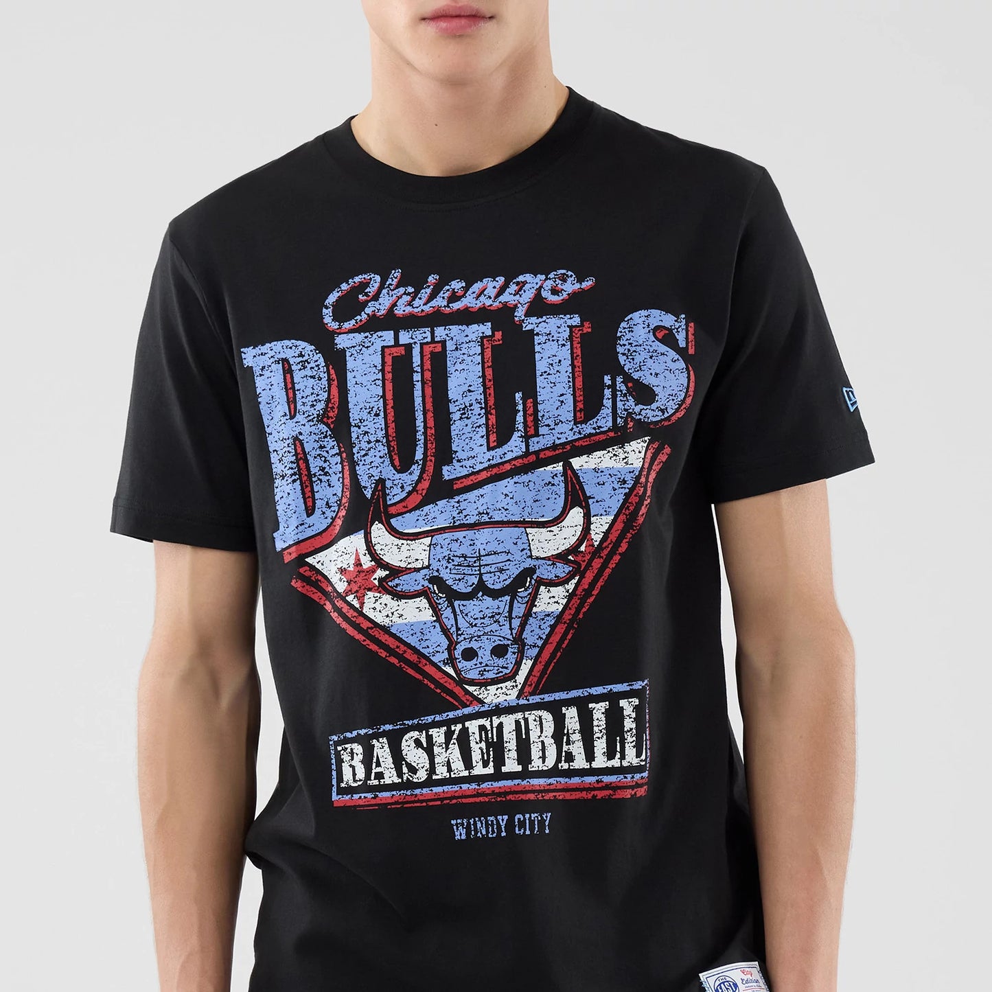 New Era Chicago Bulls NBA City Edition Black T-Shirt, front view showing a large graphic with distressed blue Chicago Bulls lettering above a stylised bull's head, basketball text below, and a small embroidered New Era logo on the sleeve.