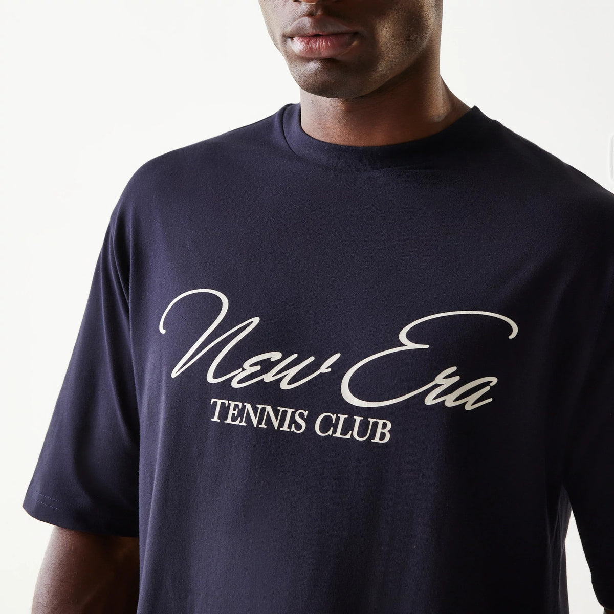 New Era Navy Oversized T-Shirt, front view on-model highlighting the white printed New Era Tennis Club script logo across the chest, with relaxed short sleeves and a high crew neckline.