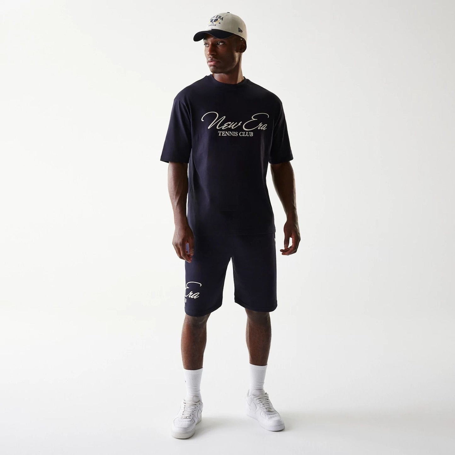 New Era Navy Oversized T-Shirt, front view on-model displaying the white script New Era Tennis Club logo across the chest, styled with matching navy shorts featuring the logo above the left knee.