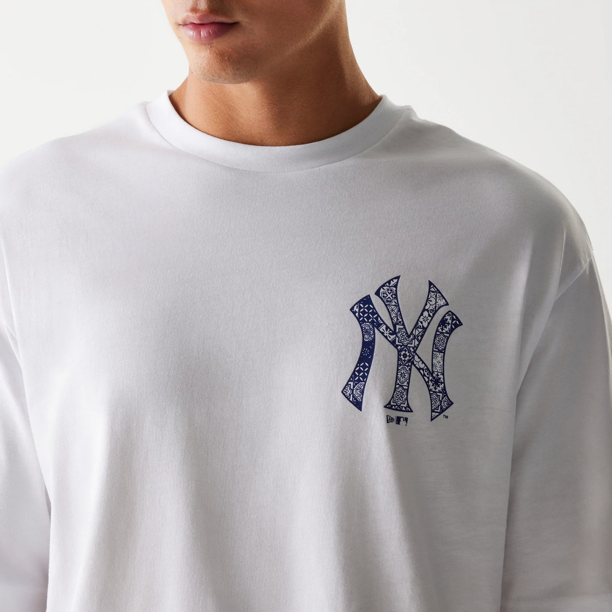New Era New York Yankees MLB White Oversized T-Shirt, front view showing the white fabric with a distinct navy printed New York Yankees logo on the left chest, worn by a model with the collar clearly outlined.