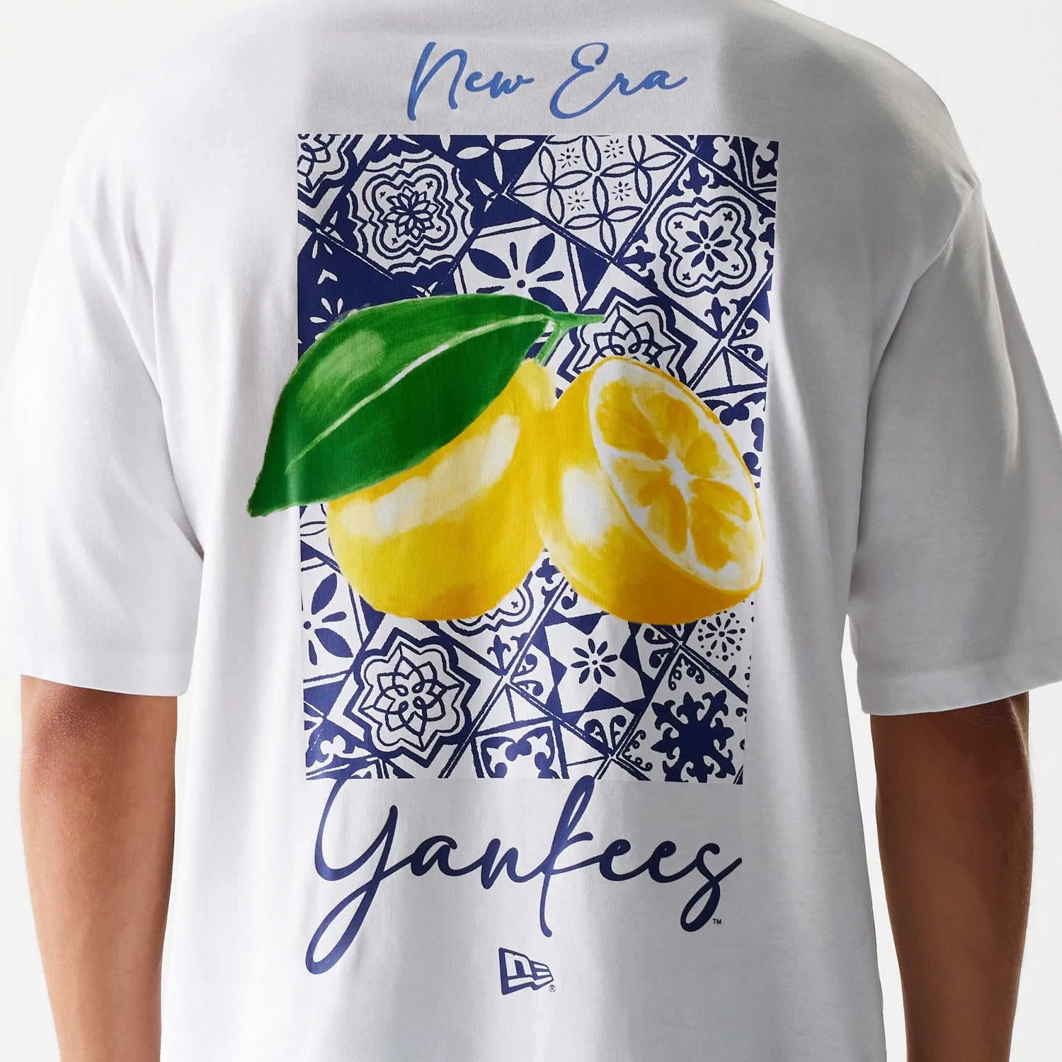 New Era New York Yankees MLB White Oversized T-Shirt, back view showing an intricate blue and white patterned rectangle with two bright yellow lemons, New Era script near the neckline.