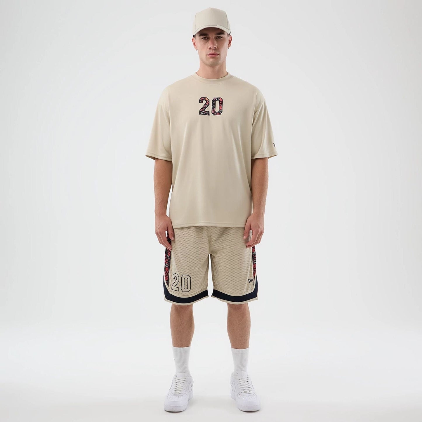 New Era Mesh Light Beige Mesh Shorts, front view on-model showing beige shorts with embroidered number 20 on the left leg, floral down the sides, and a small embroidered New Era logo near the hem.