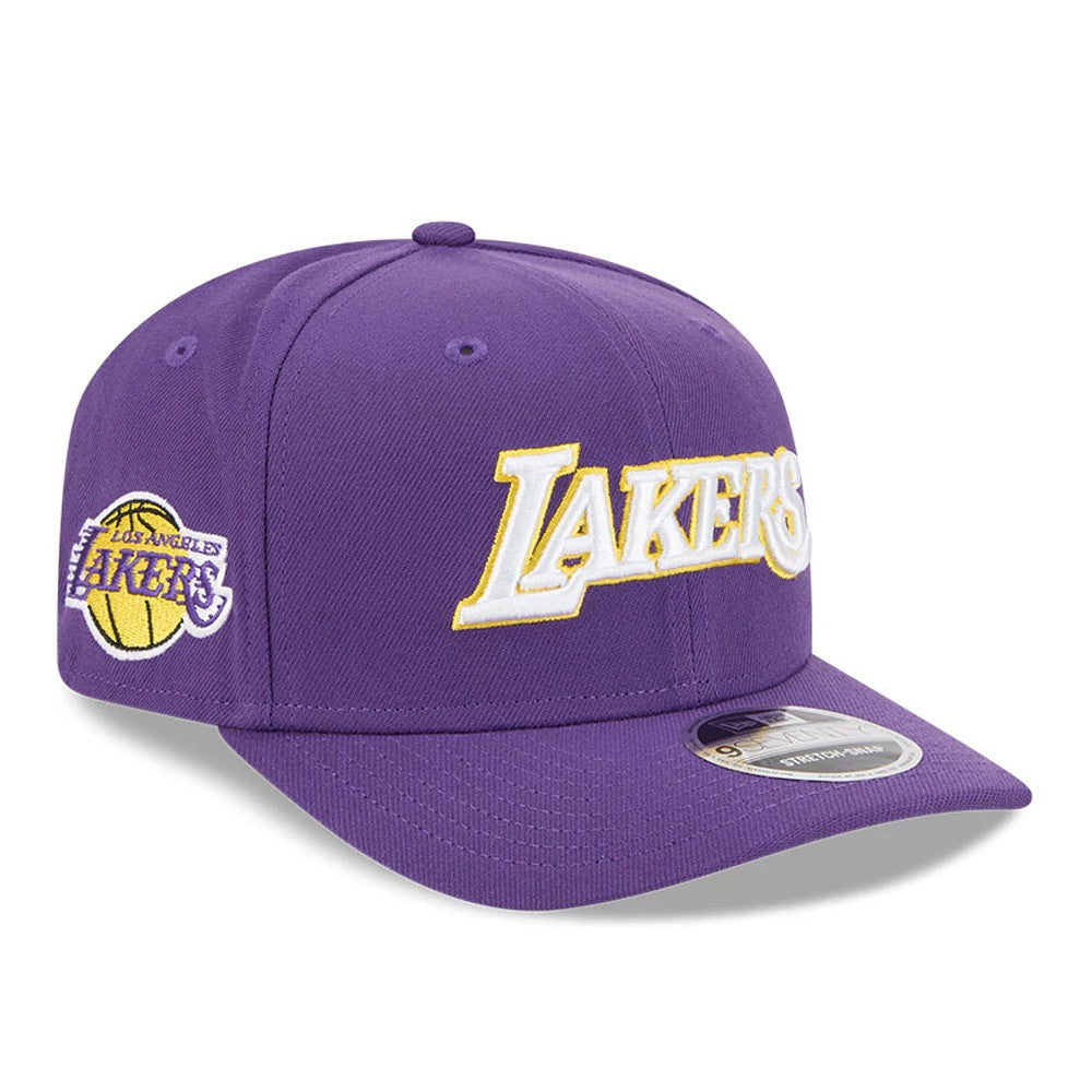 LA Lakers NBA Statement Purple New Era 9SEVENTY Stretch Snap Adjustable Cap, three-quarter view showing the raised white Lakers wordmark logo outlined in yellow across the front panels, with the Los Angeles Lakers side logo.