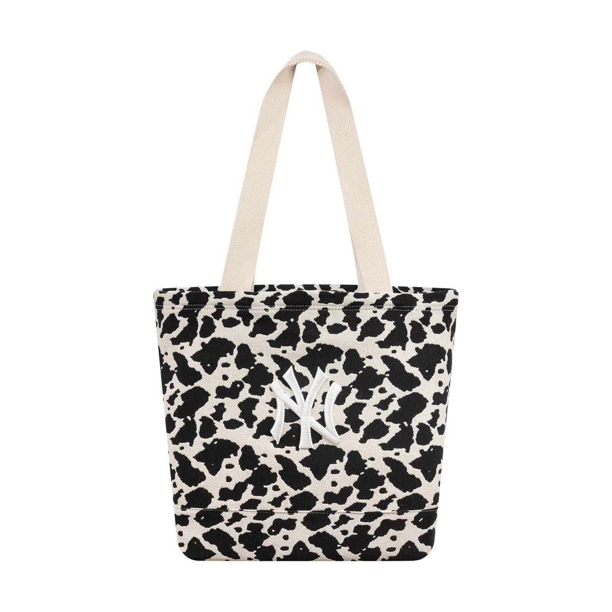New Era New York Yankees MLB Cow Jacquard Cream Tote Bag, front view showing a cow print design with black and cream spots, dual cream handles at the top, and an embroidered white New York Yankees logo on the side of the tote.