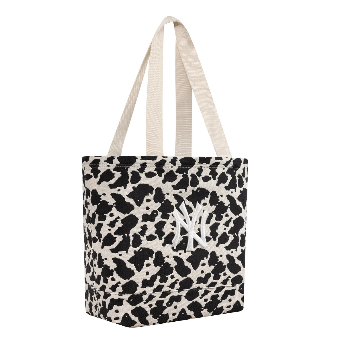 New Era New York Yankees MLB Cow Jacquard Cream Tote Bag, three-quarter view displaying the cow print pattern with a white embroidered Yankees logo on the front, featuring cream handles.