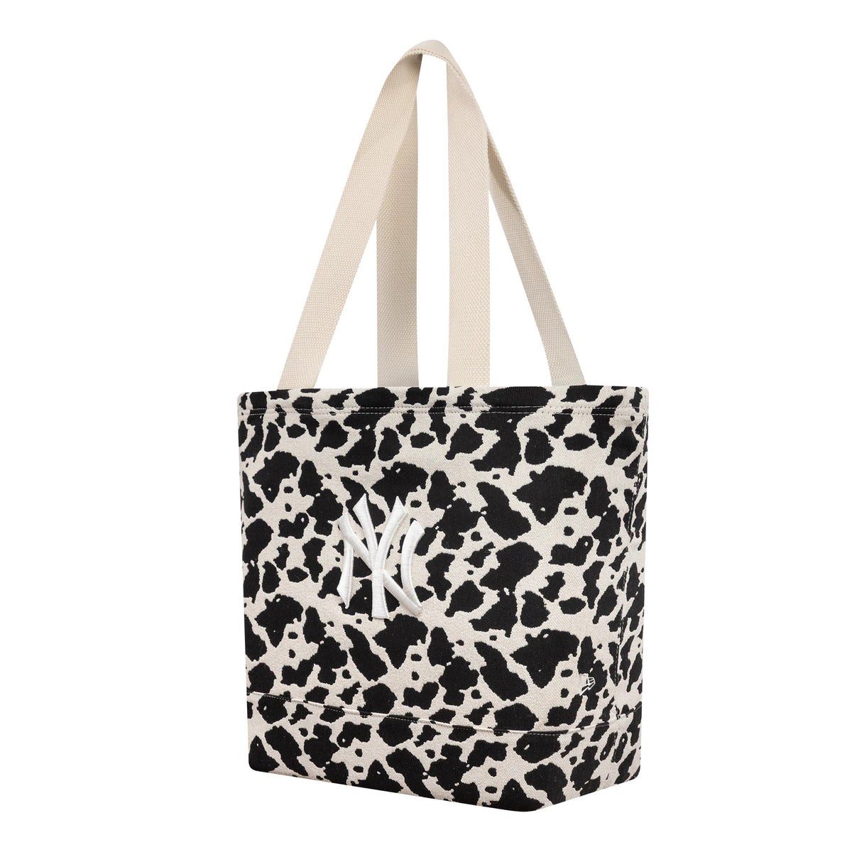 New Era New York Yankees MLB Cow Jacquard Cream Tote Bag, three-quarter view showing the cow print pattern in black and cream, with white embroidered New York Yankees logo centrally placed, and two cream handles.