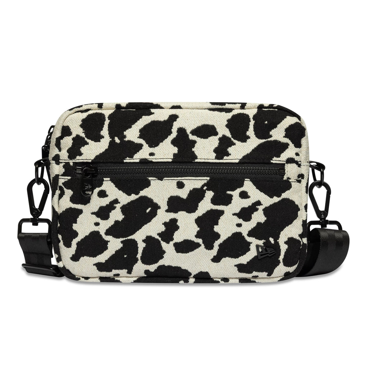 New Era Cow Jacquard Light Beige Waist Bag, front view showing the black and light beige cow print pattern, central black zip pocket, adjustable strap with clips on each side, and a raised New Era logo at the bottom corner.