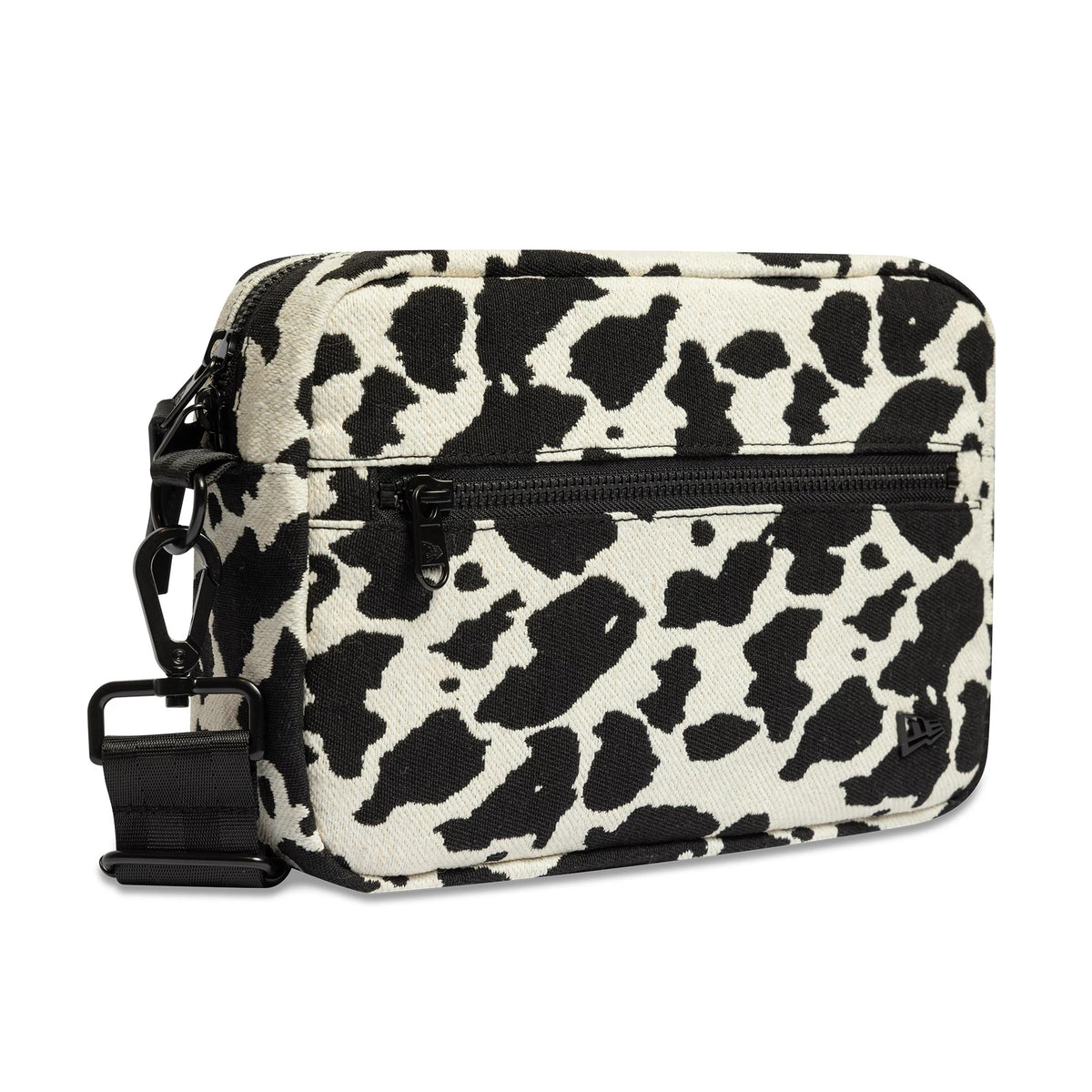 New Era Cow Jacquard Light Beige Waist Bag, side view showing the black zip pocket and clip buckle on the cow print pattern, with an embroidered New Era logo near the base on the front panel.