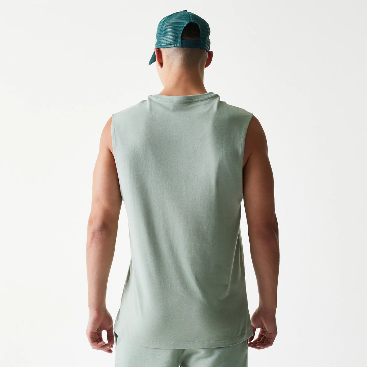 New Era LA Dodgers MLB Pastel Green Sleeveless T-Shirt, back view on-model showing the plain pastel green fabric with wide armholes, styled with a matching pastel green cap worn backwards.