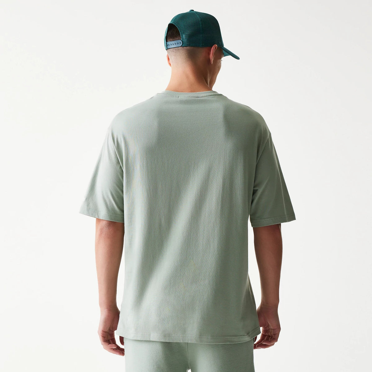 New Era LA Dodgers MLB Midi Pastel Green Oversized T-Shirt, back view on a model wearing a matching cap, displaying a plain pastel green finish with relaxed short sleeves and a straight hemline.