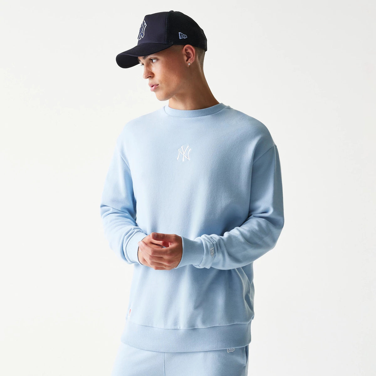 New Era New York Yankees MLB Midi Blue Oversized Crew Neck Sweater, on-model view showing the relaxed fit and white embroidered NY logo on the chest, with ribbed cuffs and hem complementing the soft blue fabric.