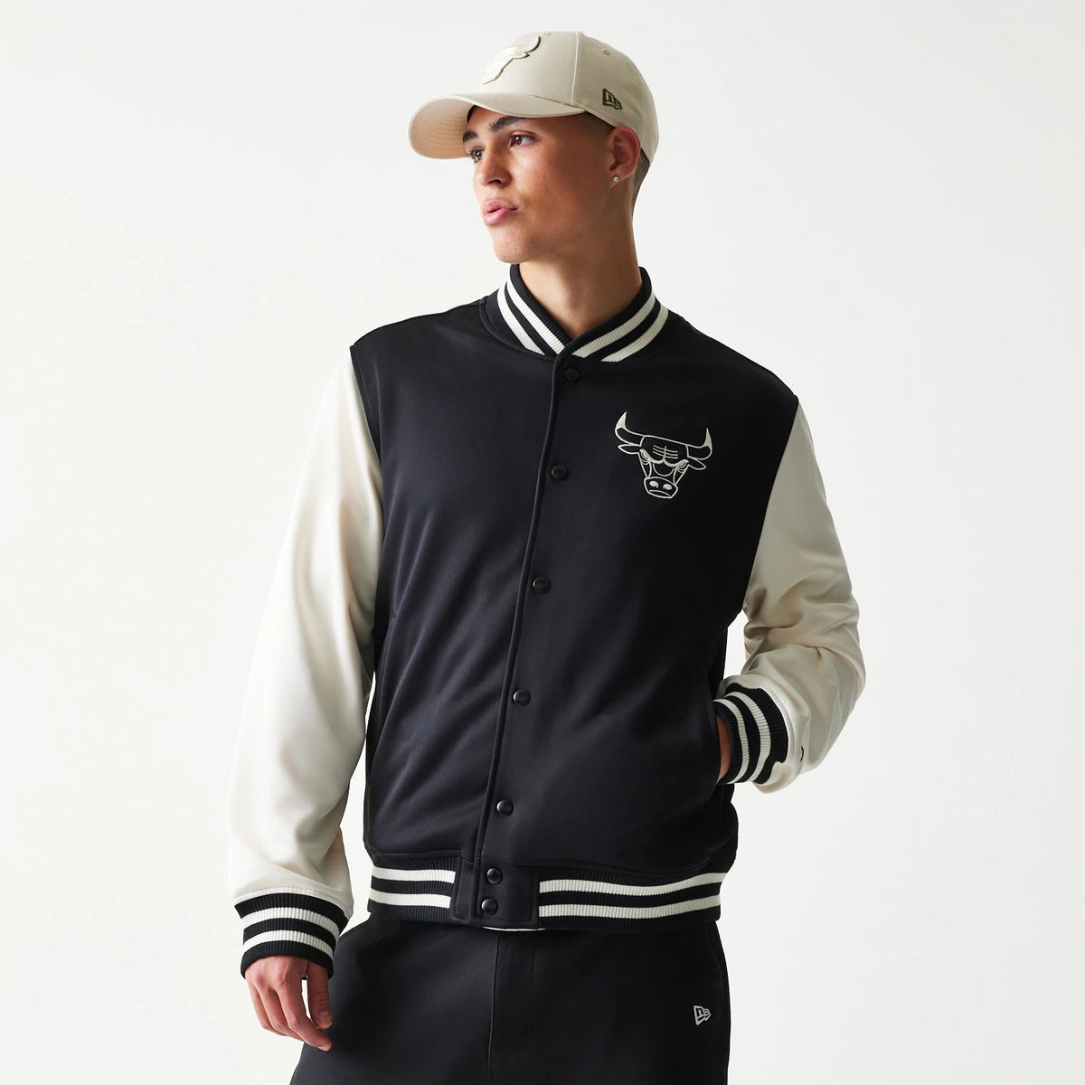 New Era Chicago Bulls NBA Black Bomber Jacket, front view on-model showing the black body contrasting with white sleeves, a black embroidered Chicago Bulls logo on the chest, and striped cuffs and collar.