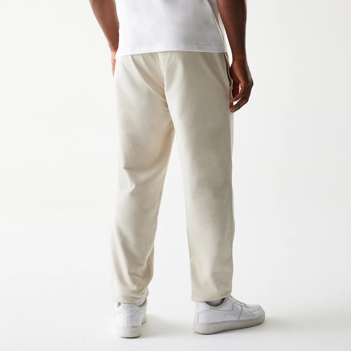 New Era LA Lakers NBA League Essential Cream Joggers, rear view on a model with a white T-shirt and trainers, showing relaxed fit, elastic waistband, and tapered legs in cream colour.