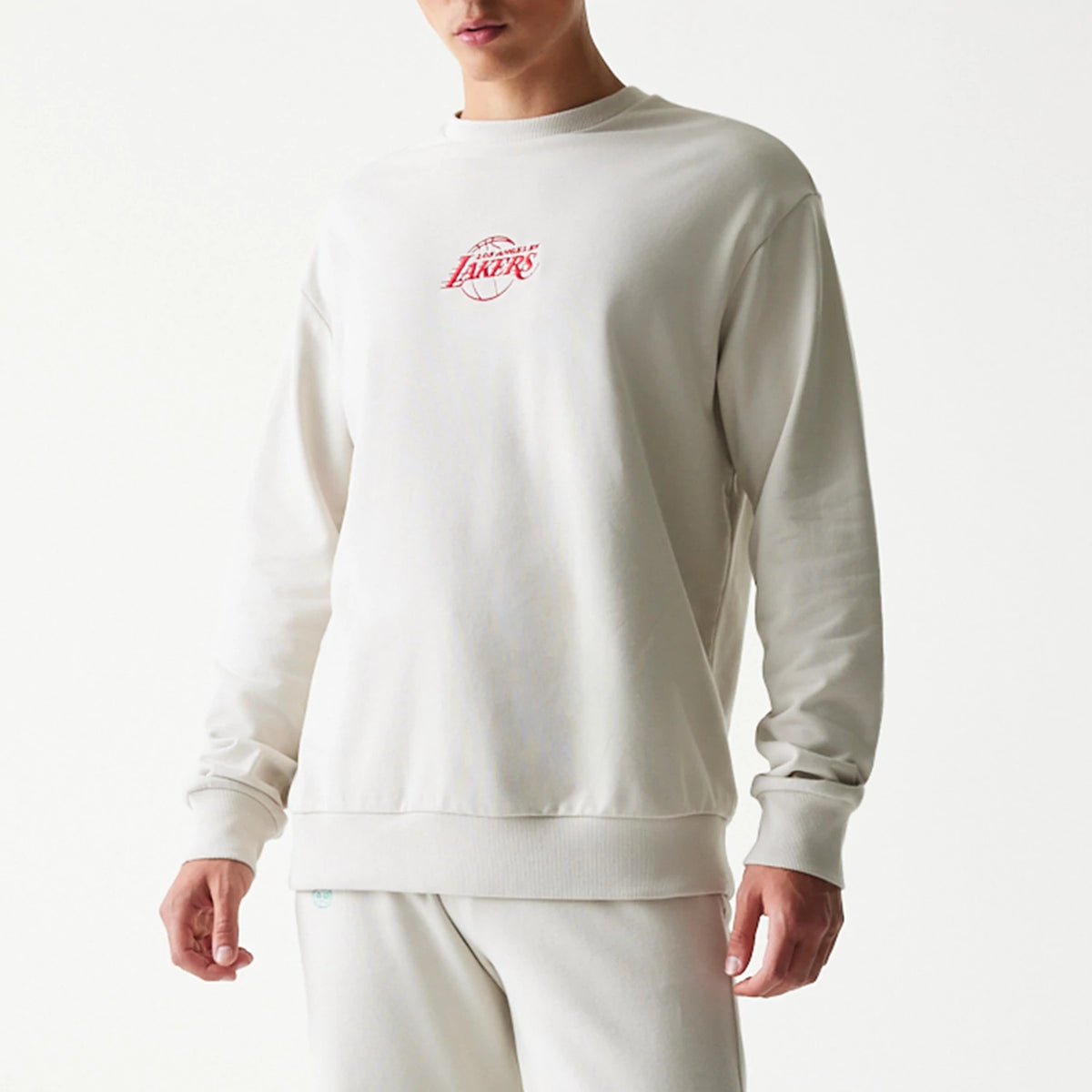 New Era LA Lakers NBA Cream Oversized Crew Neck Sweater, front view with red NBA Lakers logo embroidered on the chest, featuring ribbed cuffs and hem, shown on a model wearing matching cream joggers.