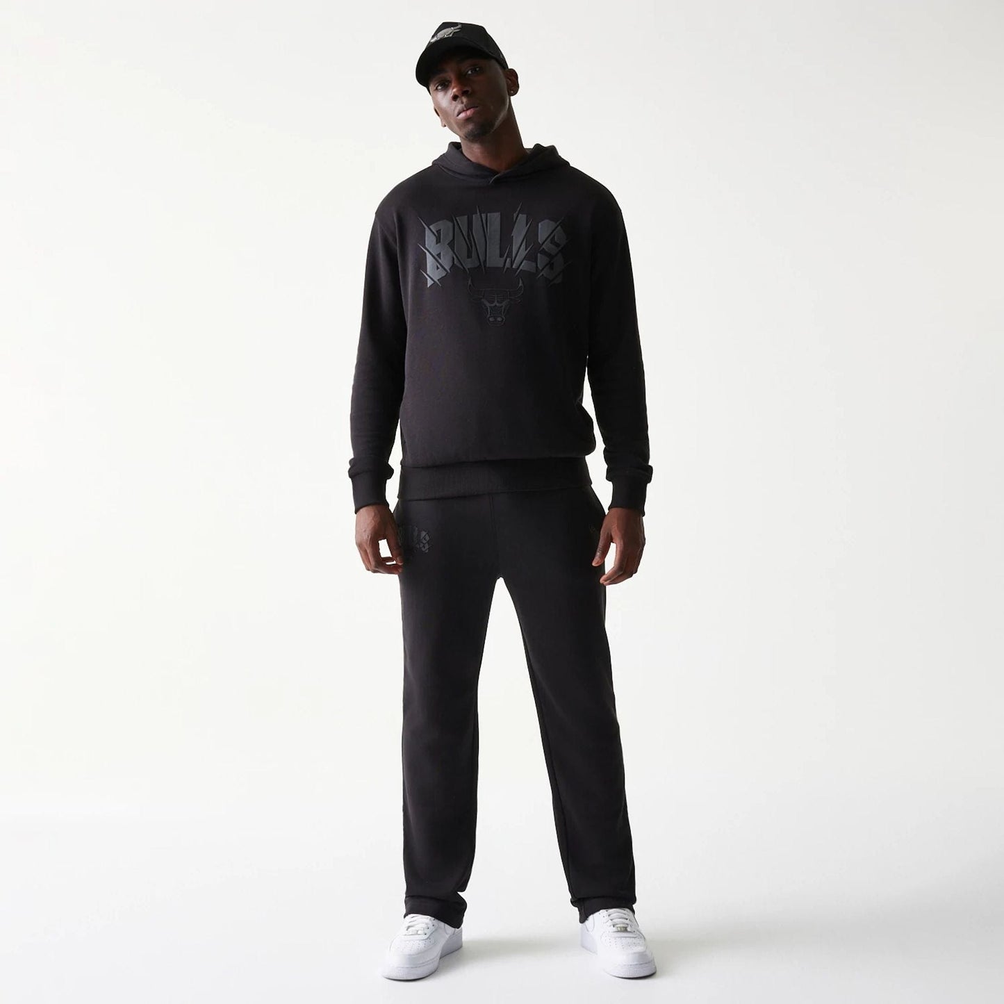 New Era Chicago Bulls NBA Black Straight Leg Joggers, front view on a model showing the Bulls logo on the left thigh, with a relaxed fit and elasticated waistband, styled with a matching hoodie and white trainers.