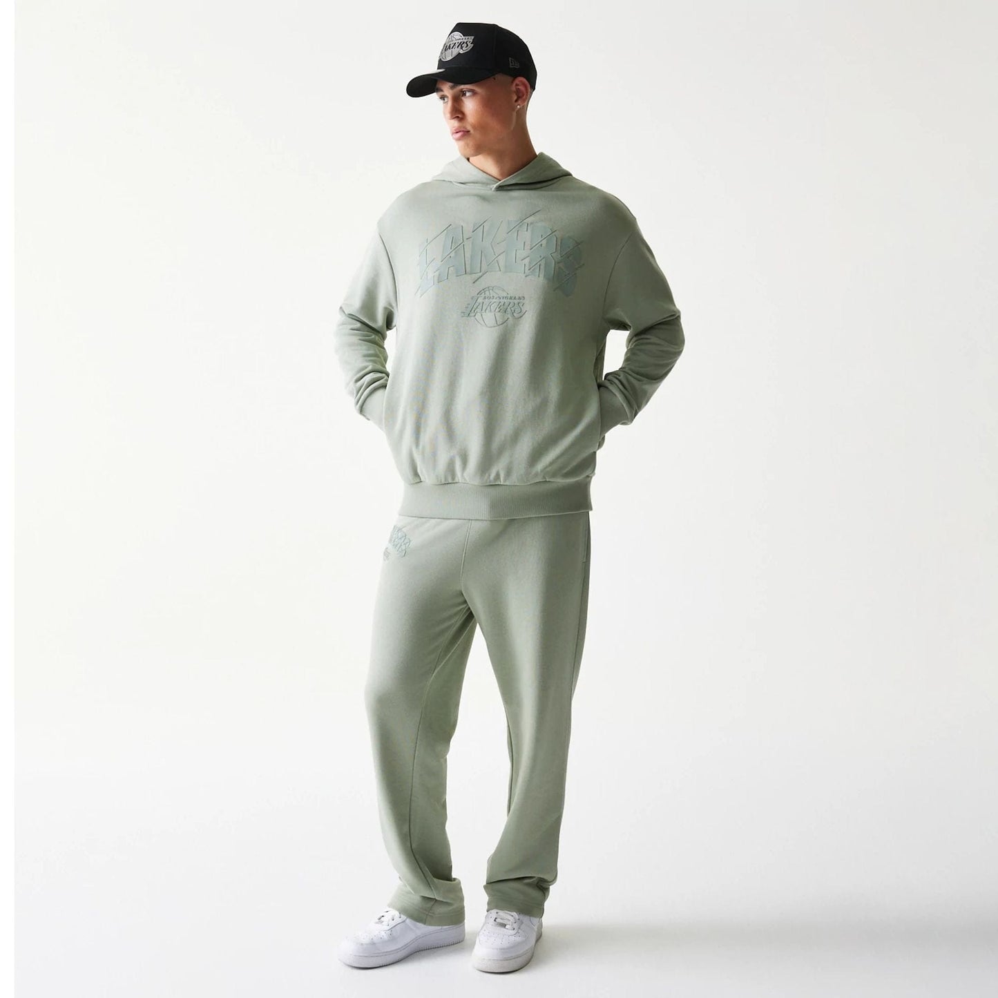 New Era LA Lakers NBA Pastel Green Oversized Pullover Hoodie, front view on-model showcasing the pastel green hue with raised Lakers lettering across the chest and matching trousers, styled with a coordinating cap.