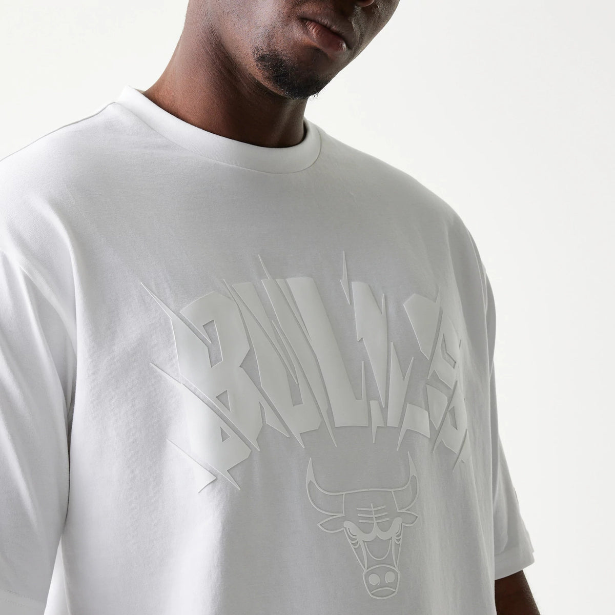 New Era Chicago Bulls NBA White Oversized T-Shirt, front view showing the embossed Bulls logo and lettering across the chest on a loose-fitting white shirt.