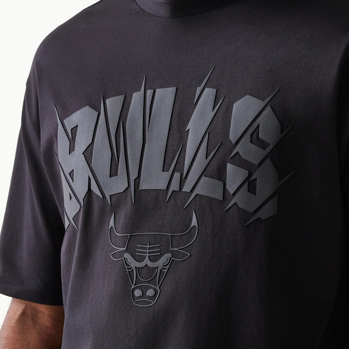 New Era Chicago Bulls NBA Black Oversized T-Shirt, front view displaying the textured design with raised Bulls lettering and the bull logo underneath, all set on the centre of the black fabric.