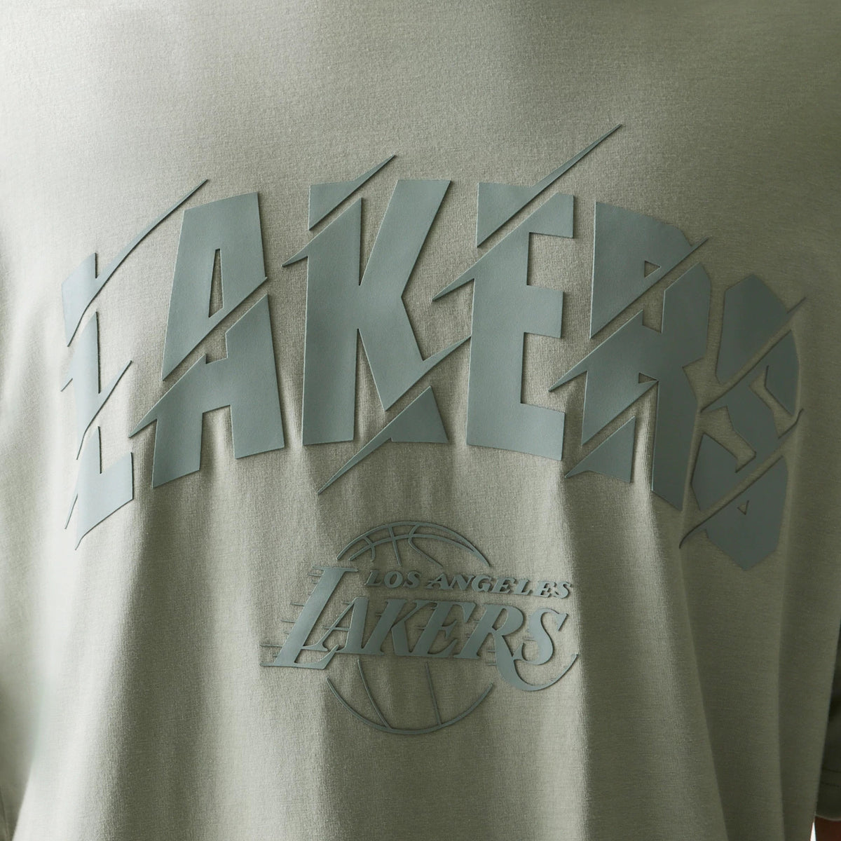 New Era LA Lakers NBA Pastel Green Oversized T-Shirt, front view showing a large raised Lakers logo in dark green across the chest with a smaller raised Los Angeles Lakers logo beneath, giving a textured appearance to the pastel green fabric.