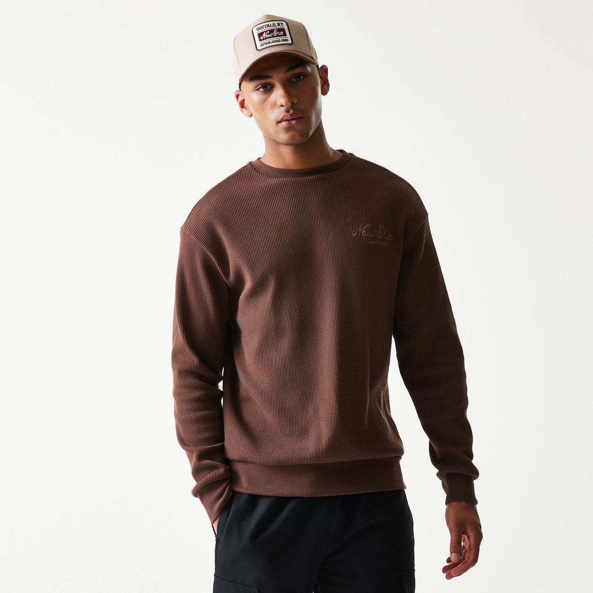 New Era Script Waffle Brown Crew Neck Sweater, front view on a model wearing a matching beige cap, featuring a embroidered New Era logo on the left chest and a ribbed neckline, cuffs and hem.