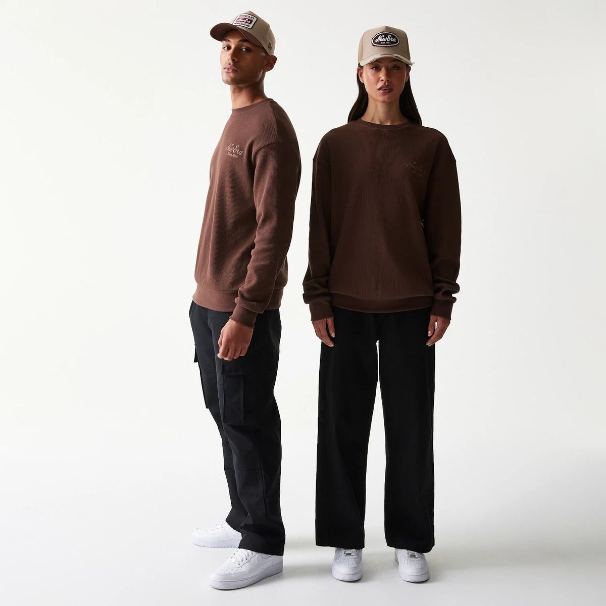 New Era Script Waffle Brown Crew Neck Sweater, on-model front view featuring the small embroidered New Era Script logo on the left chest, paired with black trousers and a neutral cap.