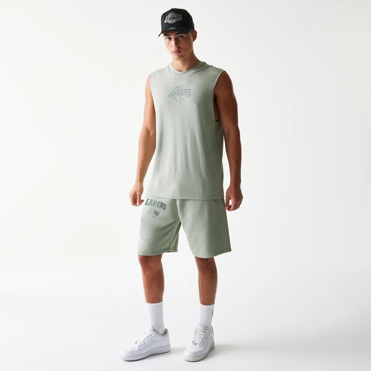 New Era LA Lakers NBA Pastel Green Shorts, on-model view showing the light green basketball team logo printed on the lower left of the shorts, paired with a matching sleeveless top and white trainers.