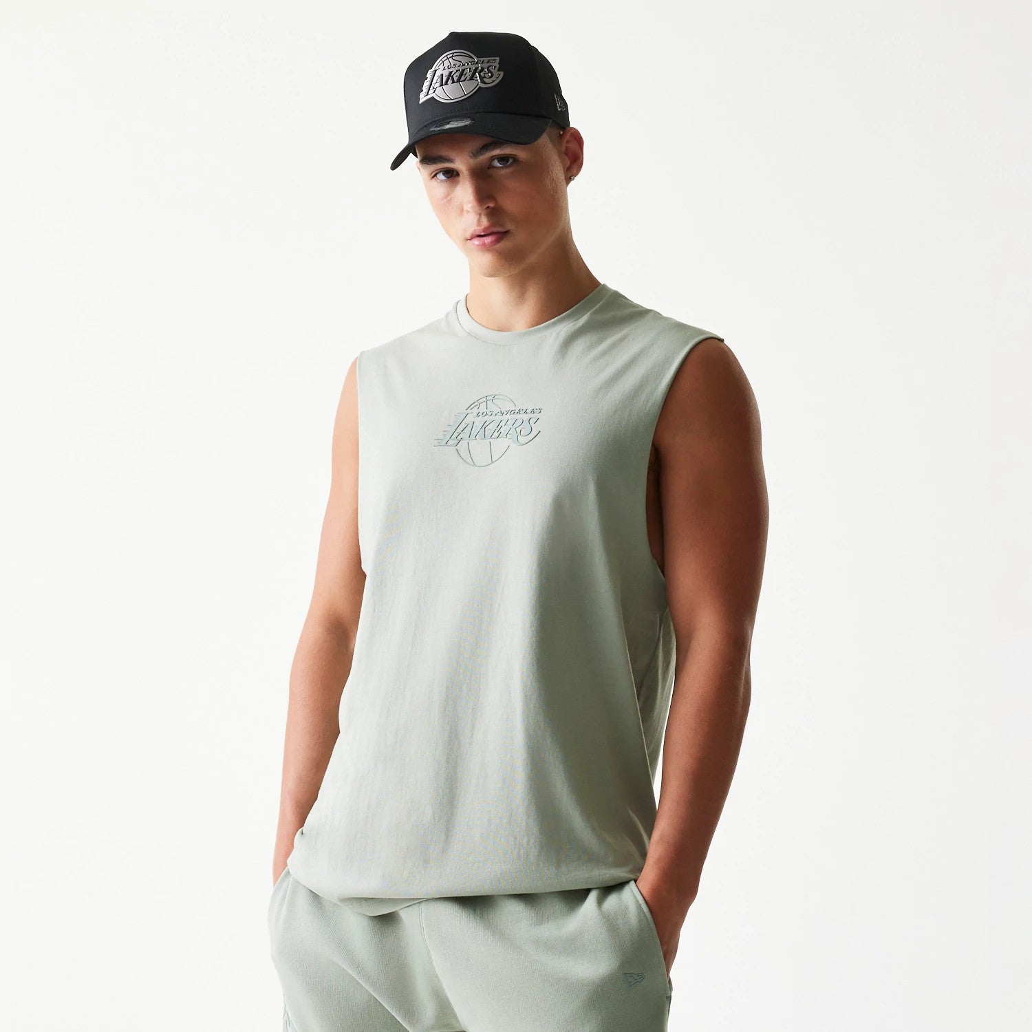 New Era LA Lakers NBA Pastel Green Sleeveless T-Shirt, front view on-model showing a pastel green design, an outlined Lakers logo in the centre, and a New Era logo above the hem with sleeveless styling.