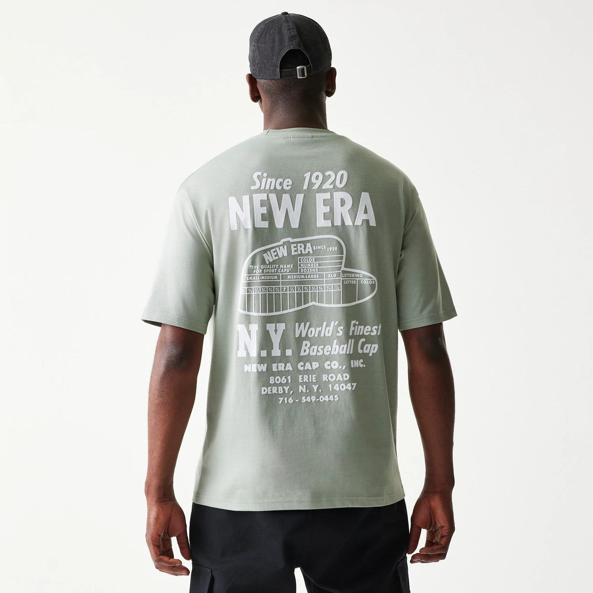 New Era Graphic Pastel Green Oversized T-Shirt, back view on a model showing large white printed lettering with the New Era logo, vintage graphics, and text the brand's legacy across the upper back.