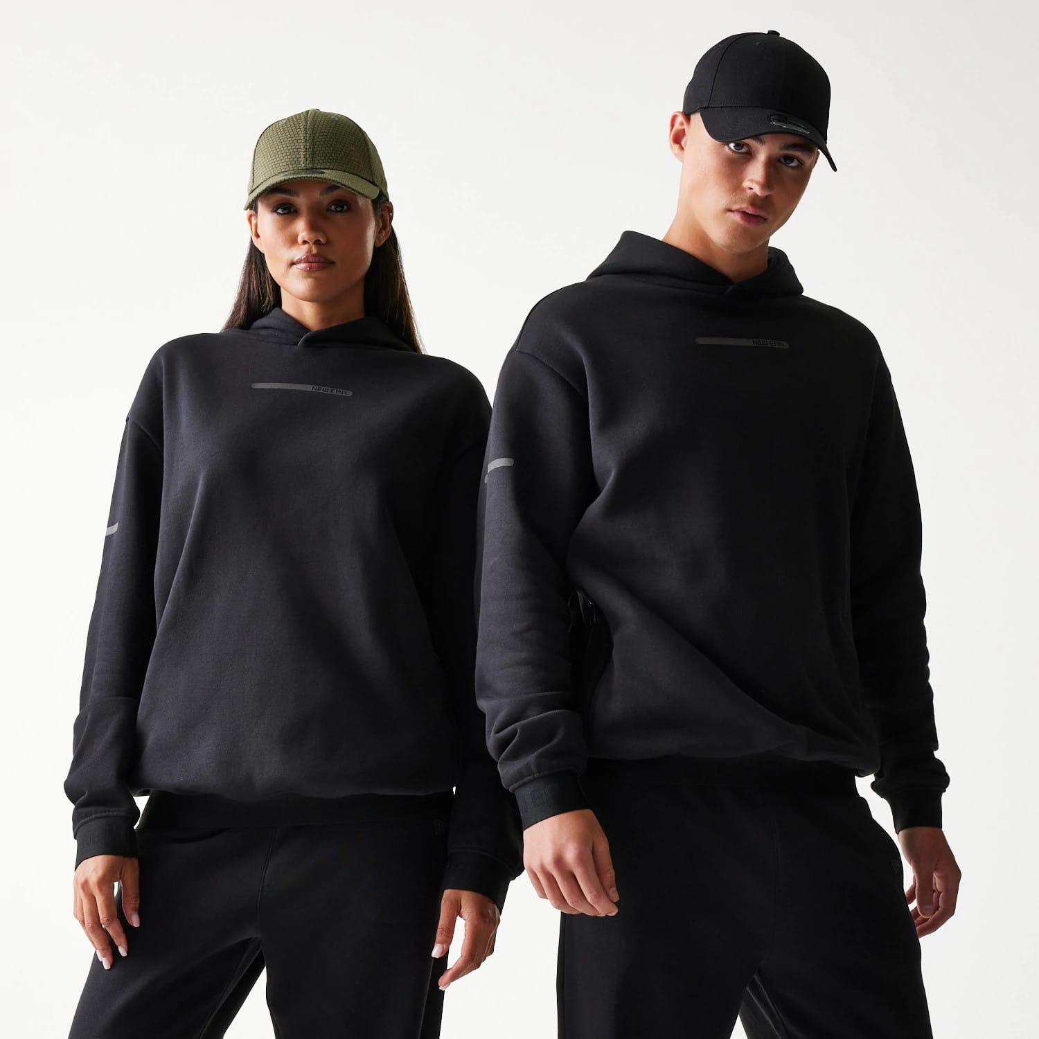The model is wearing this New Era Tech Strip Oversized Pullover Hoodie in black. 1