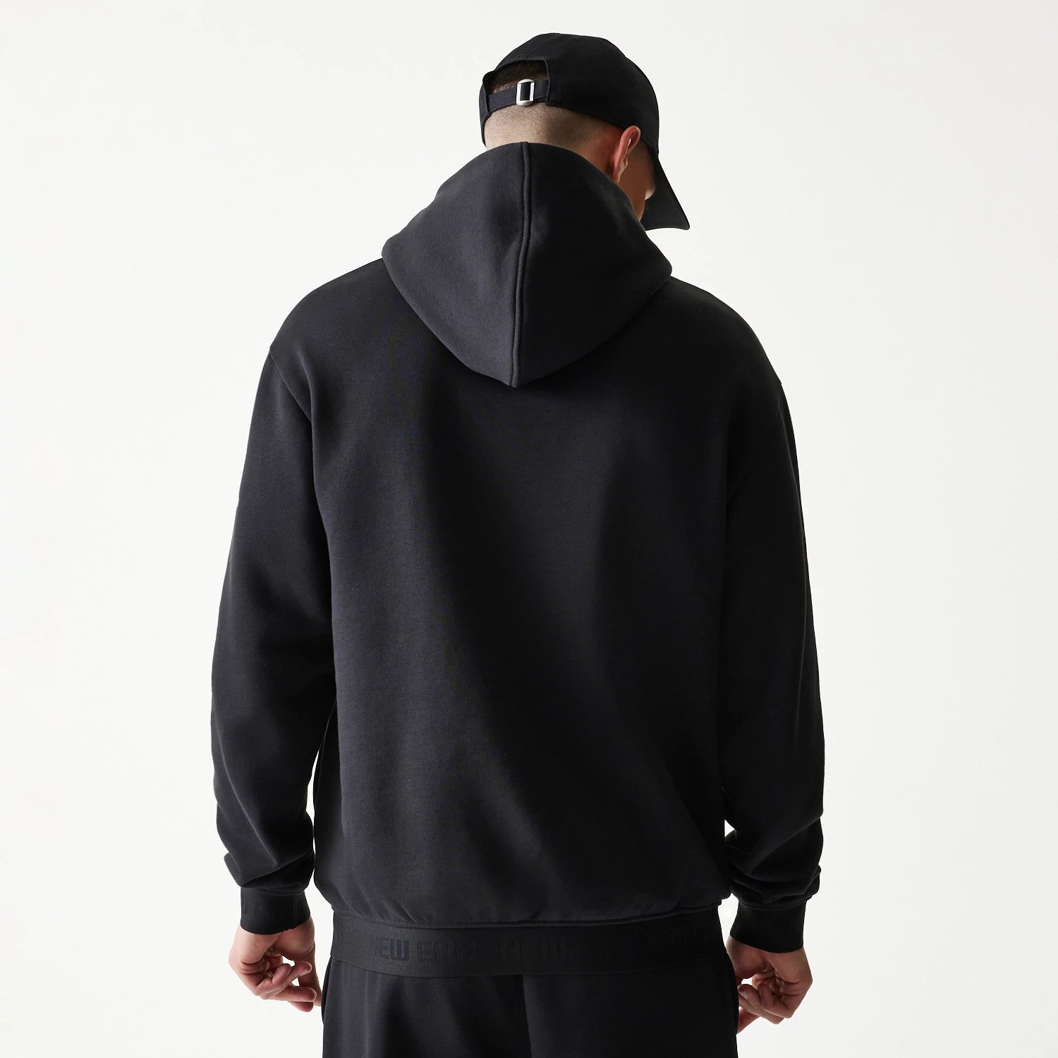 The model is wearing this New Era Tech Strip Oversized Pullover Hoodie in black. 2