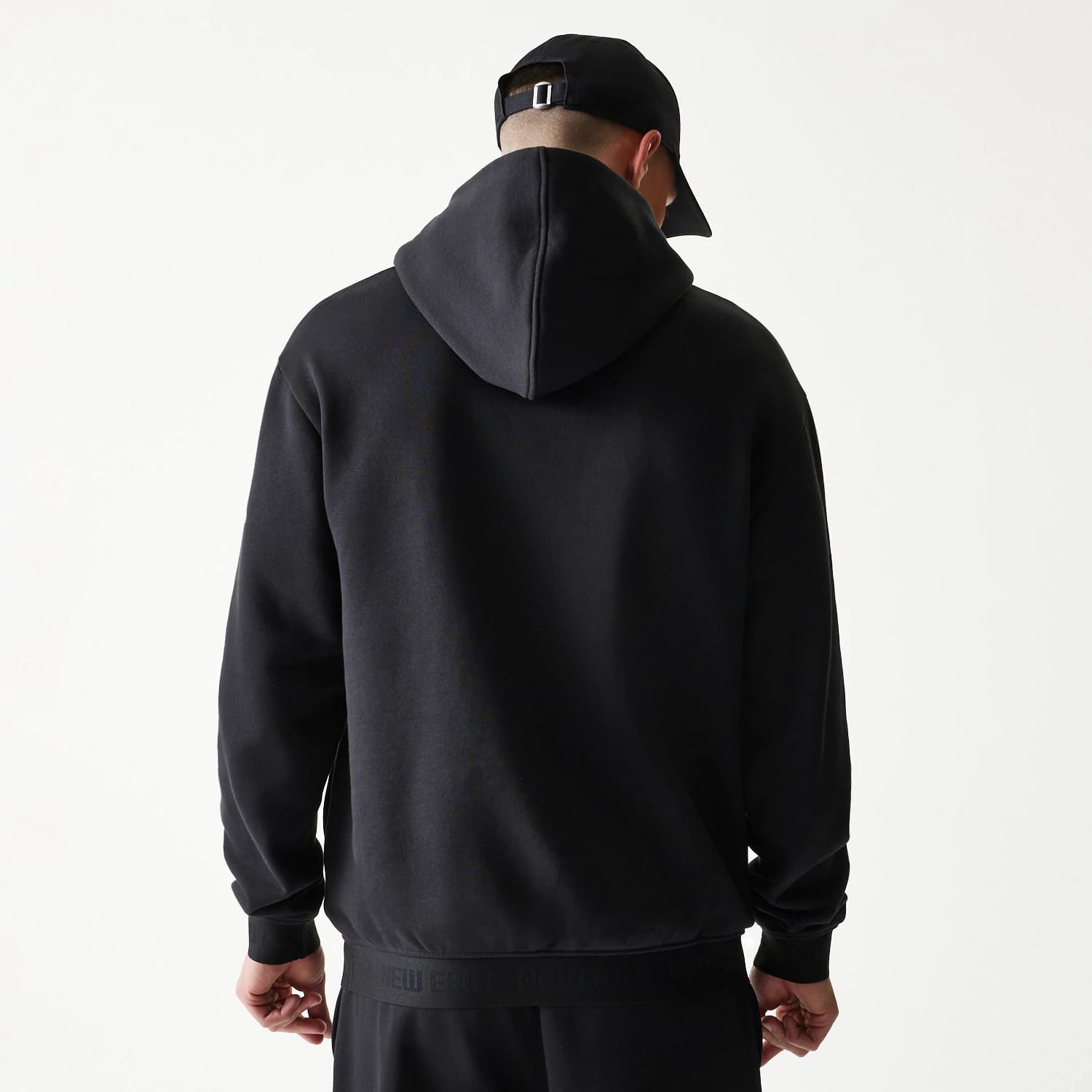 The model is wearing this New Era Tech Strip Oversized Pullover Hoodie in black. 2