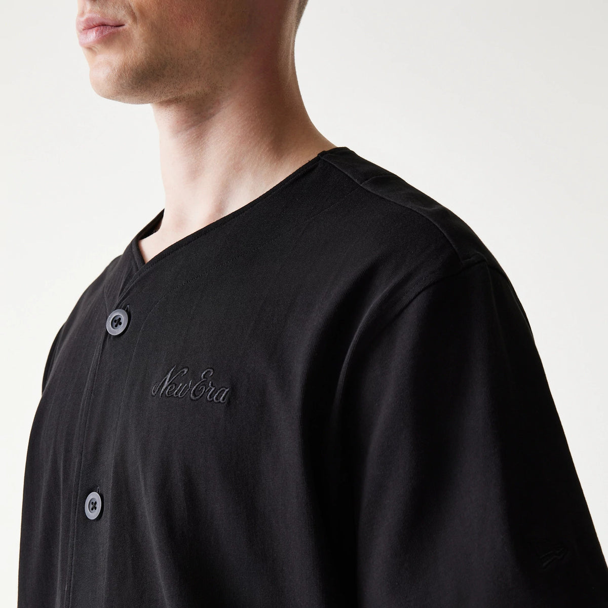 New Era Open Heritage Script Black T-Shirt, front view on-model showing full-length button design, embroidered New Era script logo prominently on the chest and a embroidered logo on the sleeve.