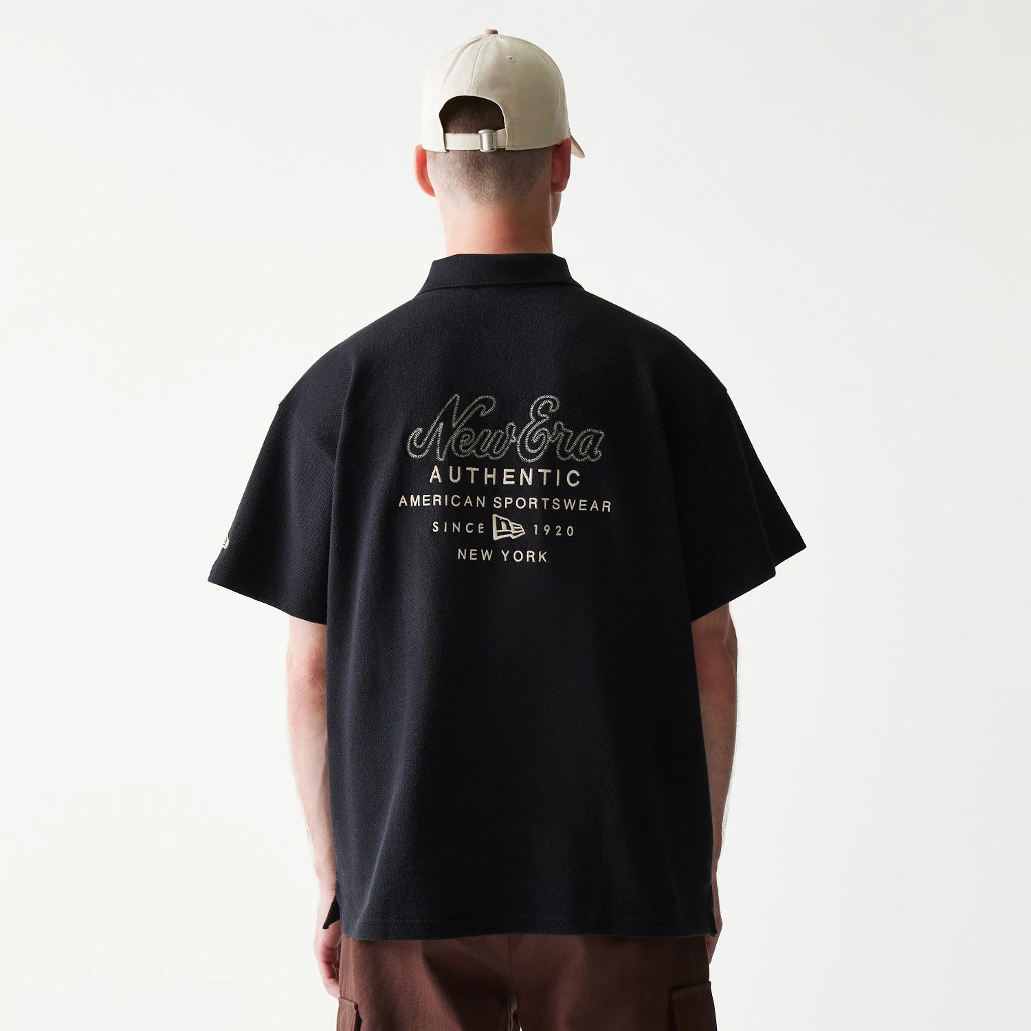 The model is wearing this New Era Graphic Polo T-Shirt in black. 2