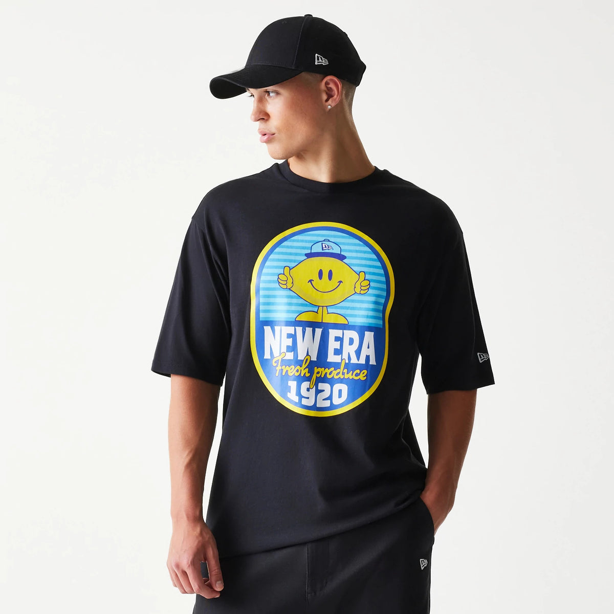 New Era Lemon Fruit Graphic Black Oversized T-Shirt, front view on-model displaying a large printed yellow lemon character graphic on the chest with New Era Fresh Produce 1920 text, and an embroidered New Era logo on the left sleeve.