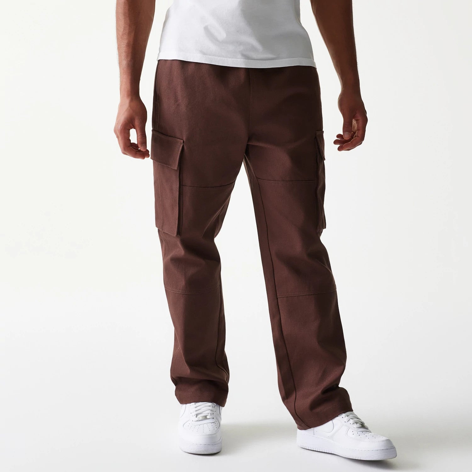 New Era Brown Straight Leg Cargo Joggers, front view on a model showing the relaxed fit with large side pockets and a tapered hem, styled with a white T-shirt and matching trainers.