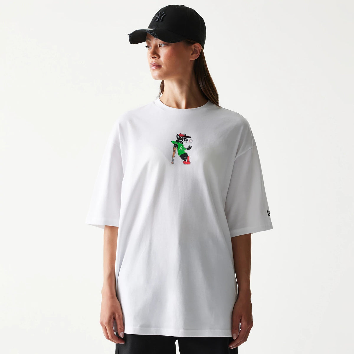 New Era Baseball Cat Character Graphic White Oversized T-Shirt, front view showing a colourful embroidered cat graphic in the centre, worn by a person in a black cap, with a small embroidered New Era logo on the sleeve.
