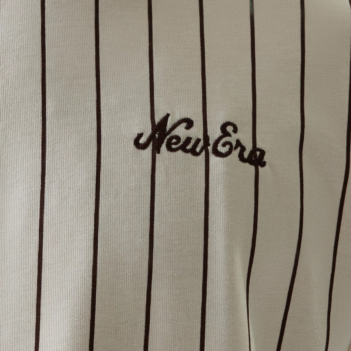 New Era Pinstripe Light Beige Oversized T-Shirt, front view showing slim vertical black pinstripes across the light beige fabric with the New Era logo prominently embroidered on the chest.