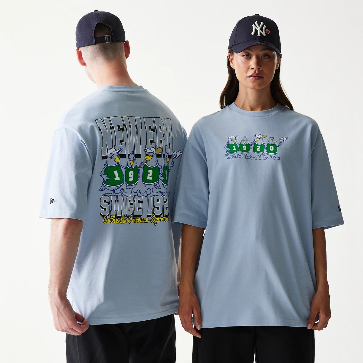 New Era Baseball Birds Character Graphic Blue Oversized T-Shirt, front and back view on models highlighting cartoon birds in green jerseys with numbers 1920 on the chest and detailed New Era lettering with Since 1920 on the back.