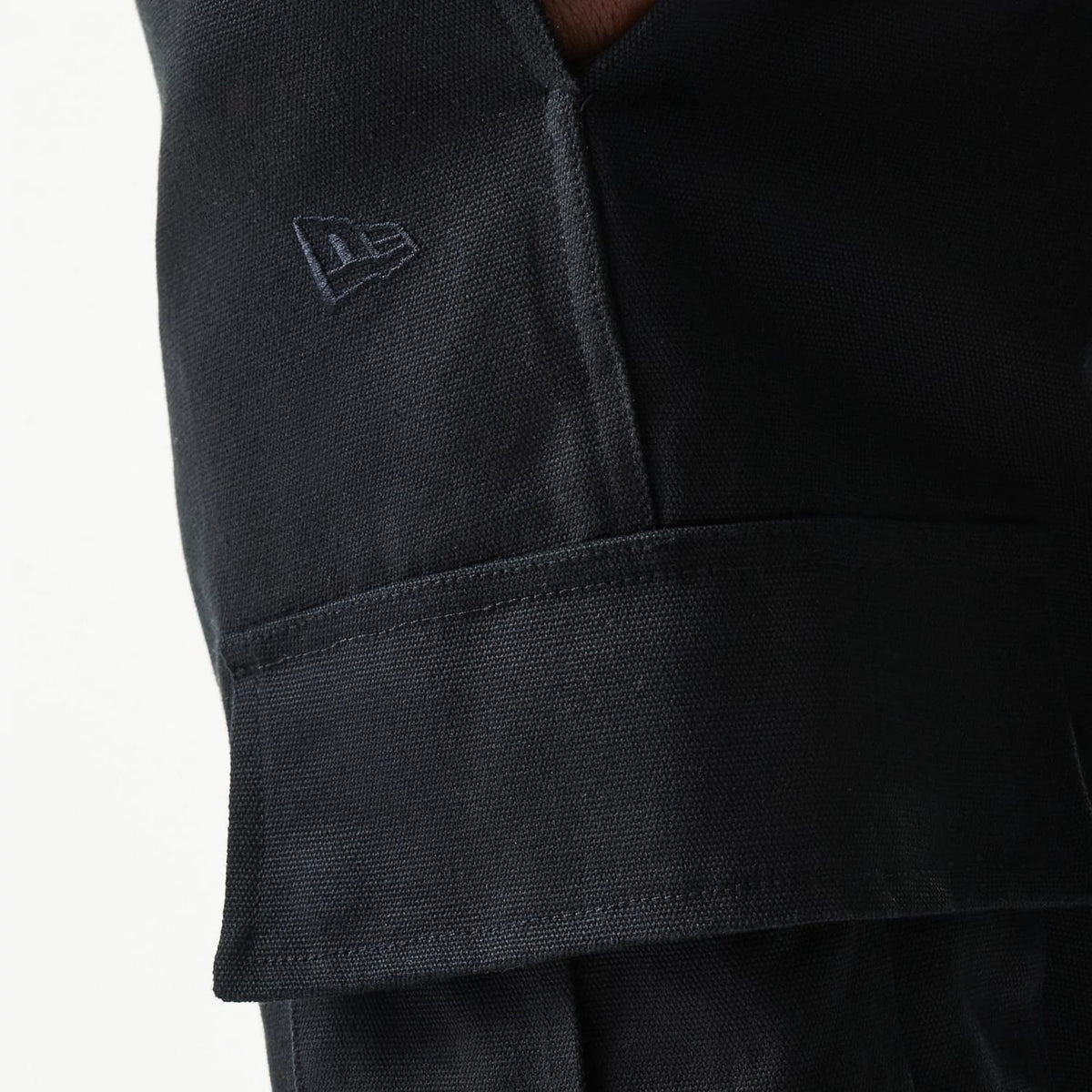 New Era Black Straight Leg Cargo Joggers, close-up view showing the textured fabric and the embroidered New Era flag logo above the flap of the side cargo pocket.