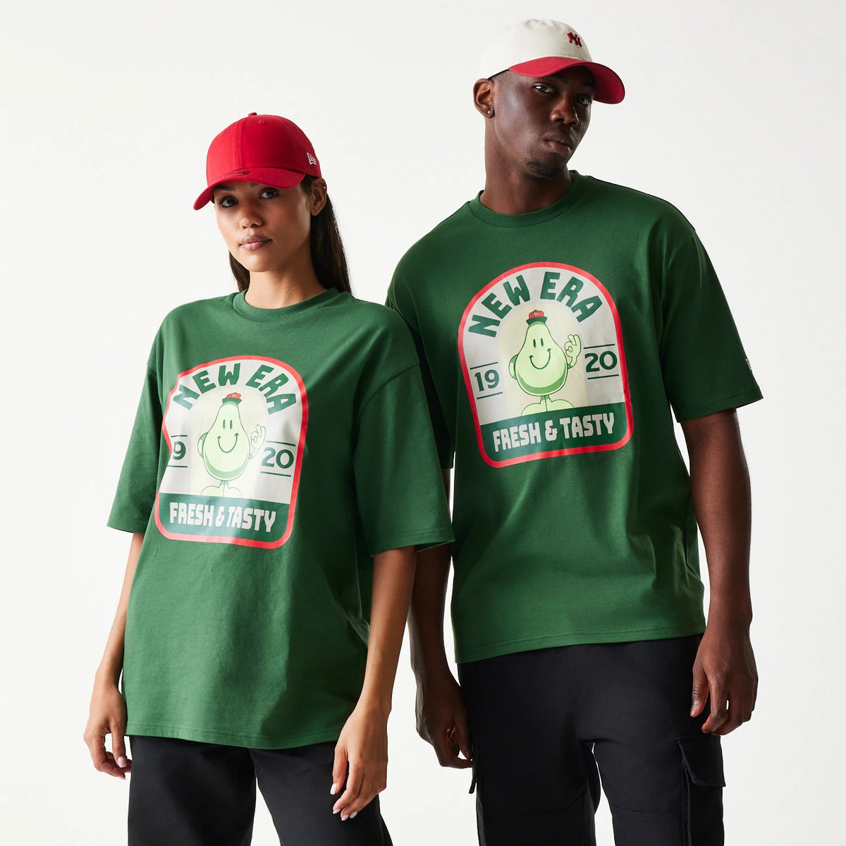 New Era Pear Fruit Graphic Dark Green Oversized T-Shirt, front view on a model showcasing a large central graphic with a smiling pear and New Era Fresh & Tasty text, detailed with the year 1920 in contrasting white and red accents.