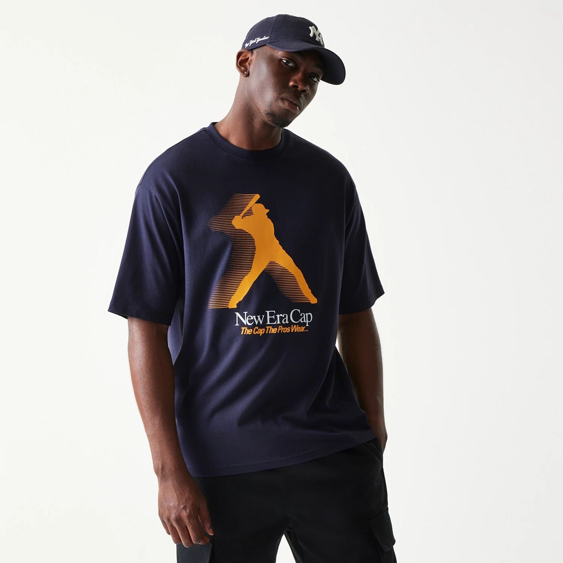 The model is wearing this New Era Baseball Player Graphic Oversized T-Shirt in navy. 1