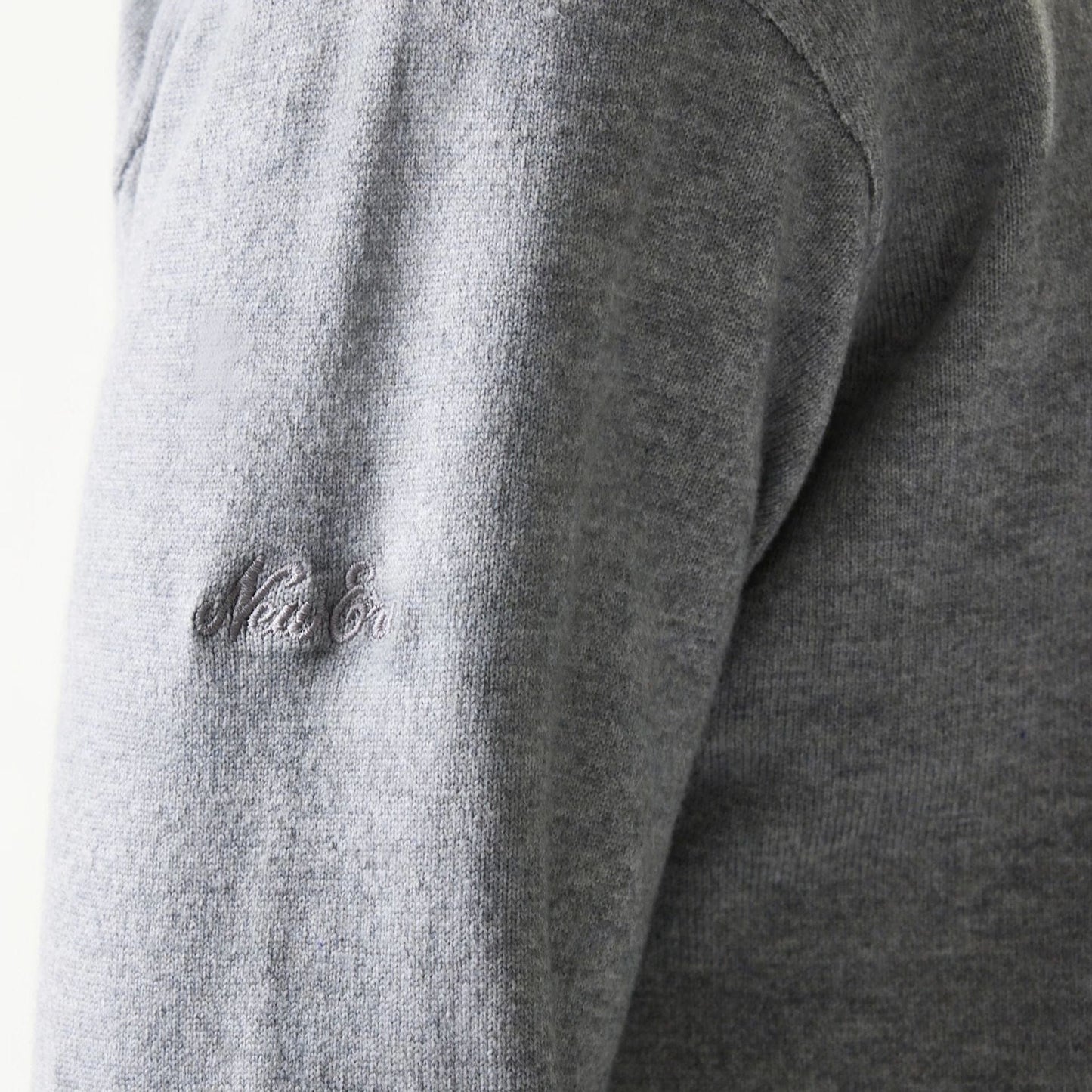New Era Essential Flag Grey Knitted Sweater, close-up showing the embroidered New Era logo in matching grey thread on the sleeve, highlighting the soft texture and fine knit of the fabric.