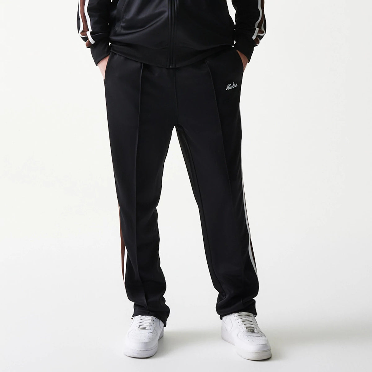 New Era Script Black Straight Leg Joggers, front view showing the white New Era script logo on the left pocket area, with side strip and a relaxed fit around the ankles paired with white trainers.