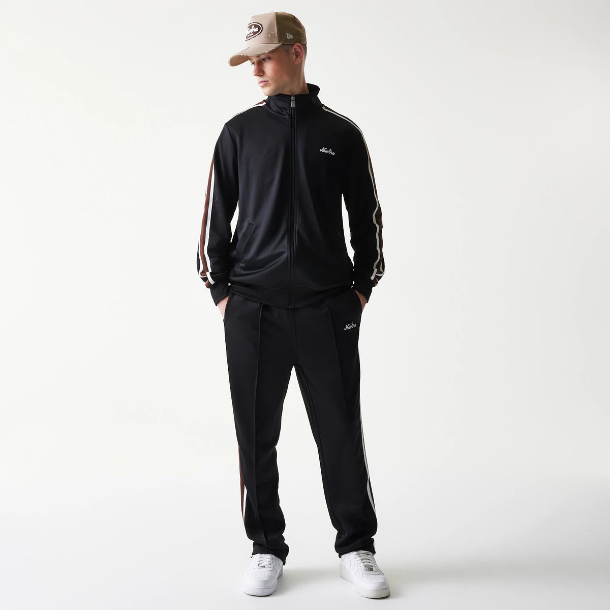 New Era Script Black Straight Leg Joggers, on-model view showcasing white embroidered script branding on the left thigh, complemented by side pockets, and paired with a matching jacket and white trainers for a look.