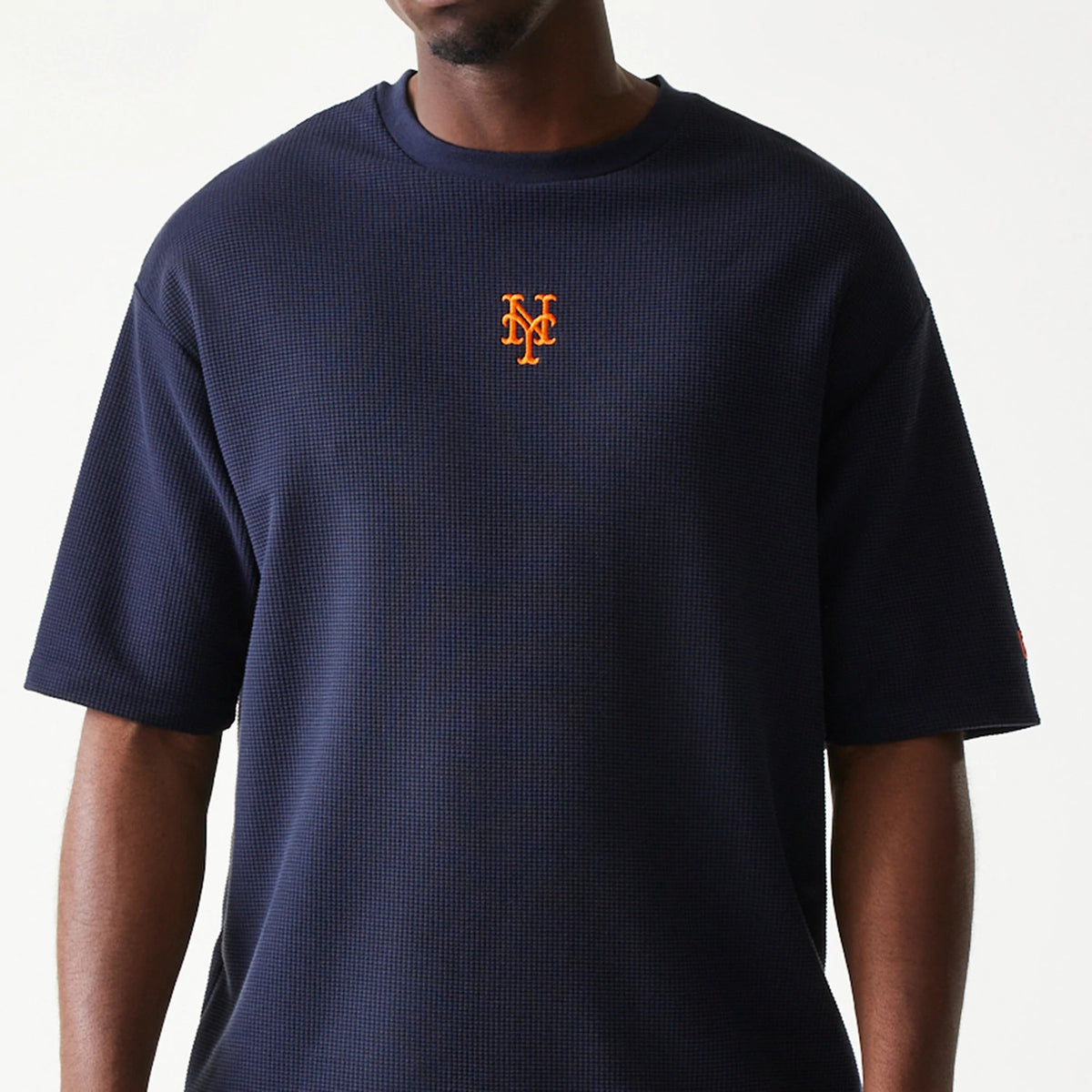 New Era New York Mets MLB Waffle Navy Oversized T-Shirt, front view on-model showing the orange embroidered Mets logo centred on the navy waffle-textured fabric, with loose fit short sleeves.