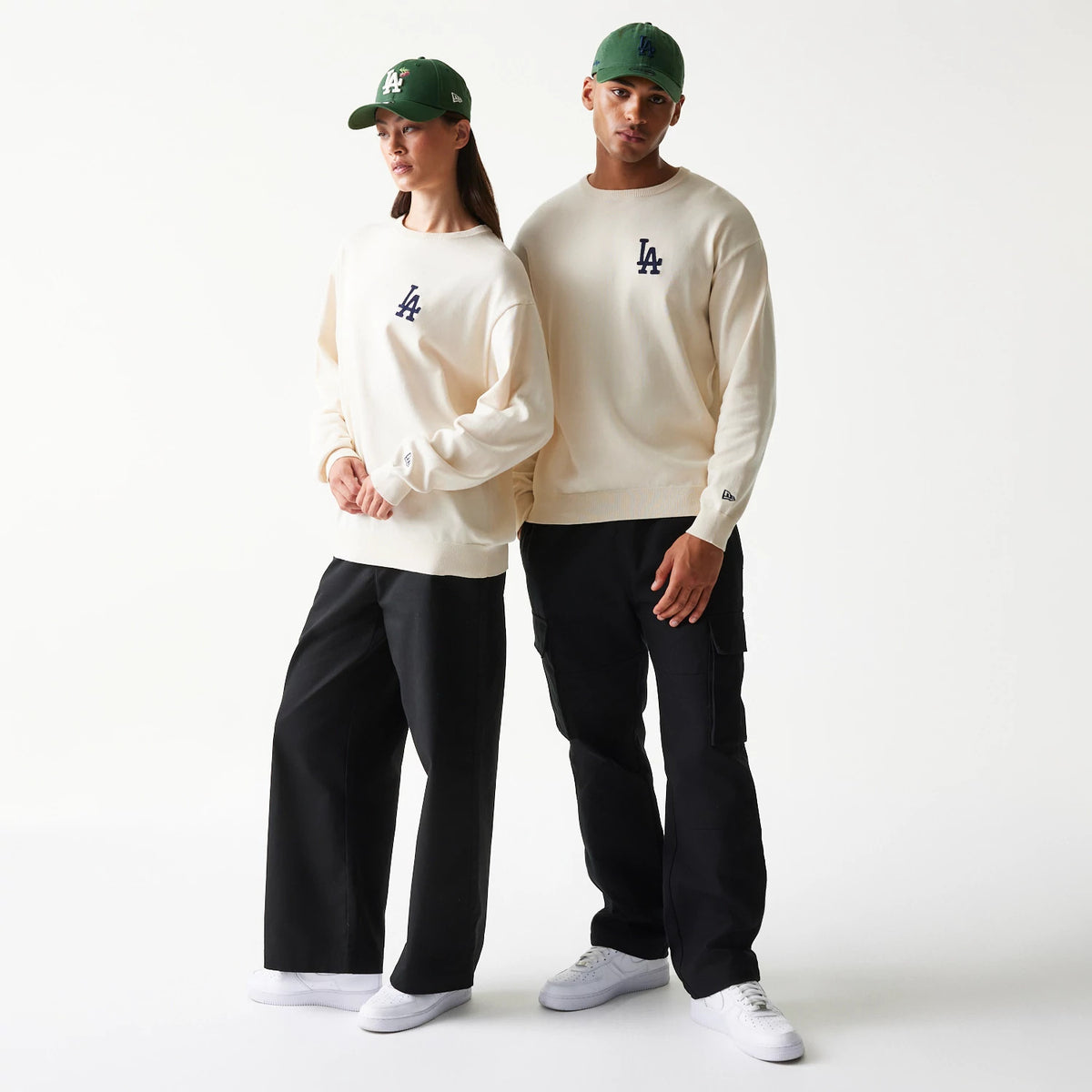 New Era LA Dodgers MLB Essential Open White Knitted Sweater, front view on a model paired with black trousers, featuring a navy LA logo embroidered on the chest and the New Era flag logo on the left wrist.