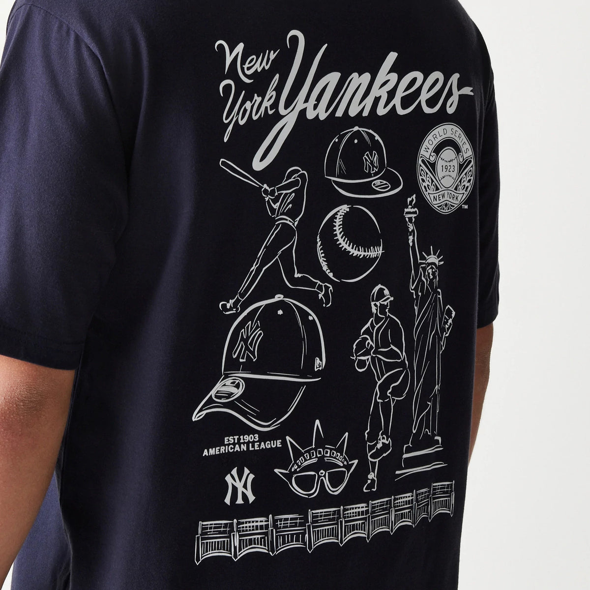 New Era New York Yankees MLB Baseball Graphic Navy Oversized T-Shirt, back view displaying white graphic illustrations including a baseball player, cap, Statue of Liberty, and World Series emblem with New York Yankees script across the top.