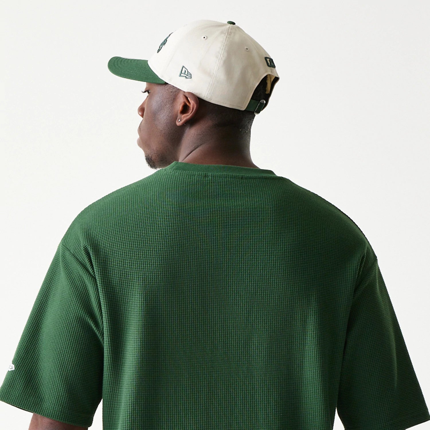 New Era LA Dodgers MLB Waffle Dark Green Oversized T-Shirt, back view on-model showing the textured dark green fabric extending across the shoulders, with a small embroidered New Era logo on the sleeve and paired with a two-tone cap.
